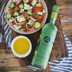 Olive oil bottle with a salad and olive oil on a wooden surface