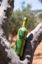 Green olive oil bottle with yellow label on a tree branch
